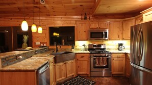 A kitchen with wooden cabinets, stainless steel appliances, and pendant lighting. - Mountain Vista Retreat-Issi is secluded, with sunset views of the Kiamichi Mnts. (Smithville)