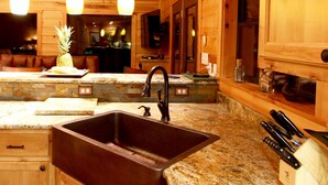 A kitchen with a granite countertop, a stainless steel sink, wooden cabinets, and a knife block. - Mountain Vista Retreat-Issi is secluded, with sunset views of the Kiamichi Mnts. (Smithville)