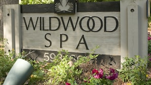 Une enseigne en bois indiquant « Wildwood Spa », avec le nom et le numéro de téléphone.