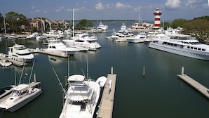 Un port de plaisance où de nombreux bateaux sont amarrés aux quais, un phare en arrière-plan et des bâtiments le long de la rive.