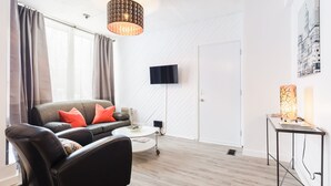 A modern living room with a sofa, a coffee table, a TV, and a lamp.