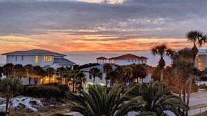 A residential area with houses and palm trees under a sunset sky.
