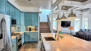 A modern kitchen with teal cabinets, stainless steel appliances, and a large island.