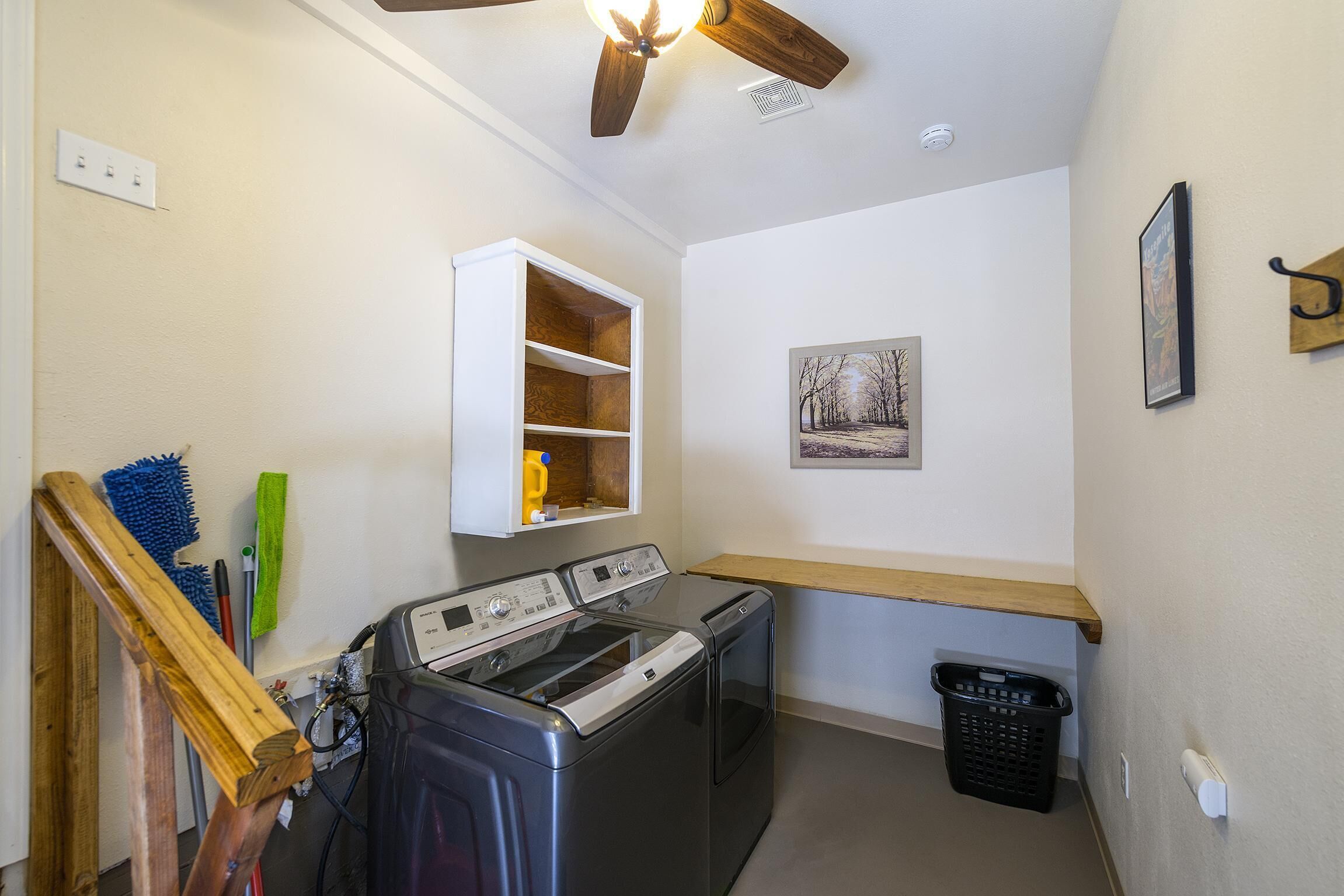 Une buanderie équipée d’un lave-linge, d’un sèche-linge, d’une étagère en bois et d’un étendoir mural.
