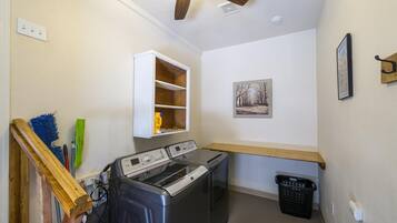 Une buanderie équipée d’un lave-linge, d’un sèche-linge, d’une étagère en bois et d’un étendoir mural.