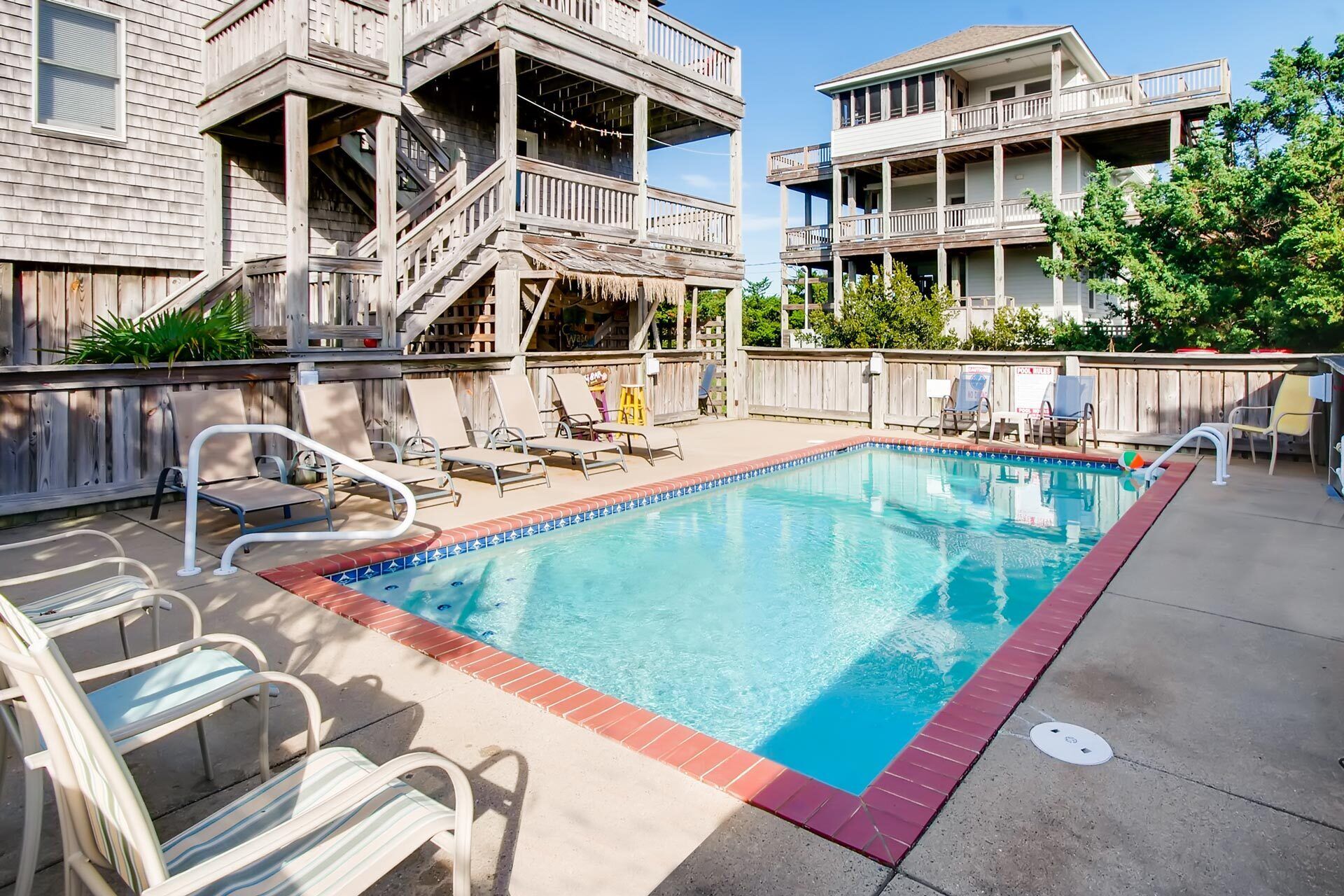 A swimming pool with lounge chairs and a wooden deck.