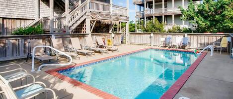 A swimming pool with lounge chairs and a wooden deck.