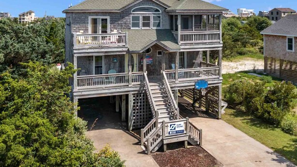 Une maison à deux étages dotée d’un balcon, d’une terrasse et d’un escalier menant à une zone abritée.