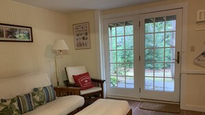 Une pièce comprenant un lit, une chaise, une lampe et une porte donnant sur un jardin.