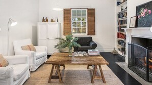 Ein Wohnzimmer mit Couchtisch aus Holz, weißen Sofas, einem Kamin und einem Bücherregal.
