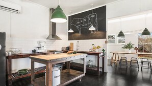 Eine moderne Küche mit Holztisch, rollbarem Wagen, Pendelleuchten und einem Metzgerdiagramm an der Wand.