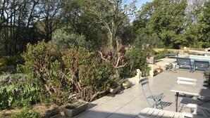 An outdoor patio area with tiled flooring, several benches, and potted plants. - Comfortable villa, heated pool in a quiet area, excluding subdivision (Sainte-Anastasie)