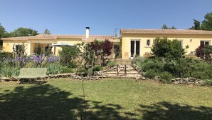 A two-story yellow building with a tiled roof, a stone pathway leading to the entrance, and a bench in the front yard. - Comfortable villa, heated pool in a quiet area, excluding subdivision (Sainte-Anastasie)