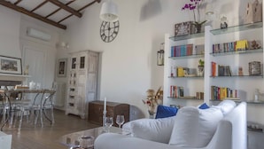 A spacious living area with a white sofa, a coffee table, and a bookshelf.
