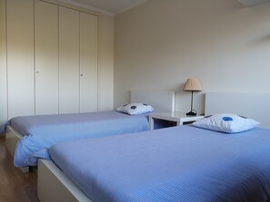A hotel room with two beds, a nightstand, a lamp, and a wardrobe. - Amazing View - Beach - Golf Resort (Herdade da Aroeira)