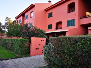 A multi-story building with a red facade, green shutters, and a gated entrance. - Amazing View - Beach - Golf Resort (Herdade da Aroeira)