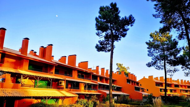 Um hotel com vários edifícios laranja, céu claro e algumas árvores.