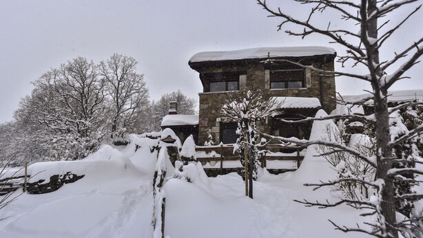 A stone building with a snow-covered roof and a wooden fence in a snowy landscape. - Spa in the house and an unbeatable view of Gredos. (San Juan de Gredos)
