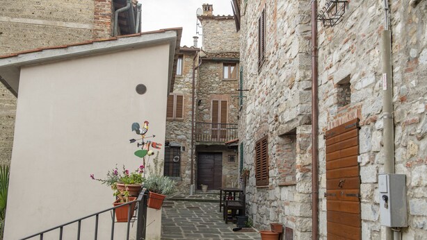 A narrow stone-paved alleyway with traditional buildings, wooden shutters, and potted plants. - La Casina di Pia in Alta Maremma (Montieri)