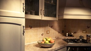 A kitchen with a bowl of fruit on the counter, a stove, and cabinets. - La Casina di Pia in Alta Maremma (Montieri)