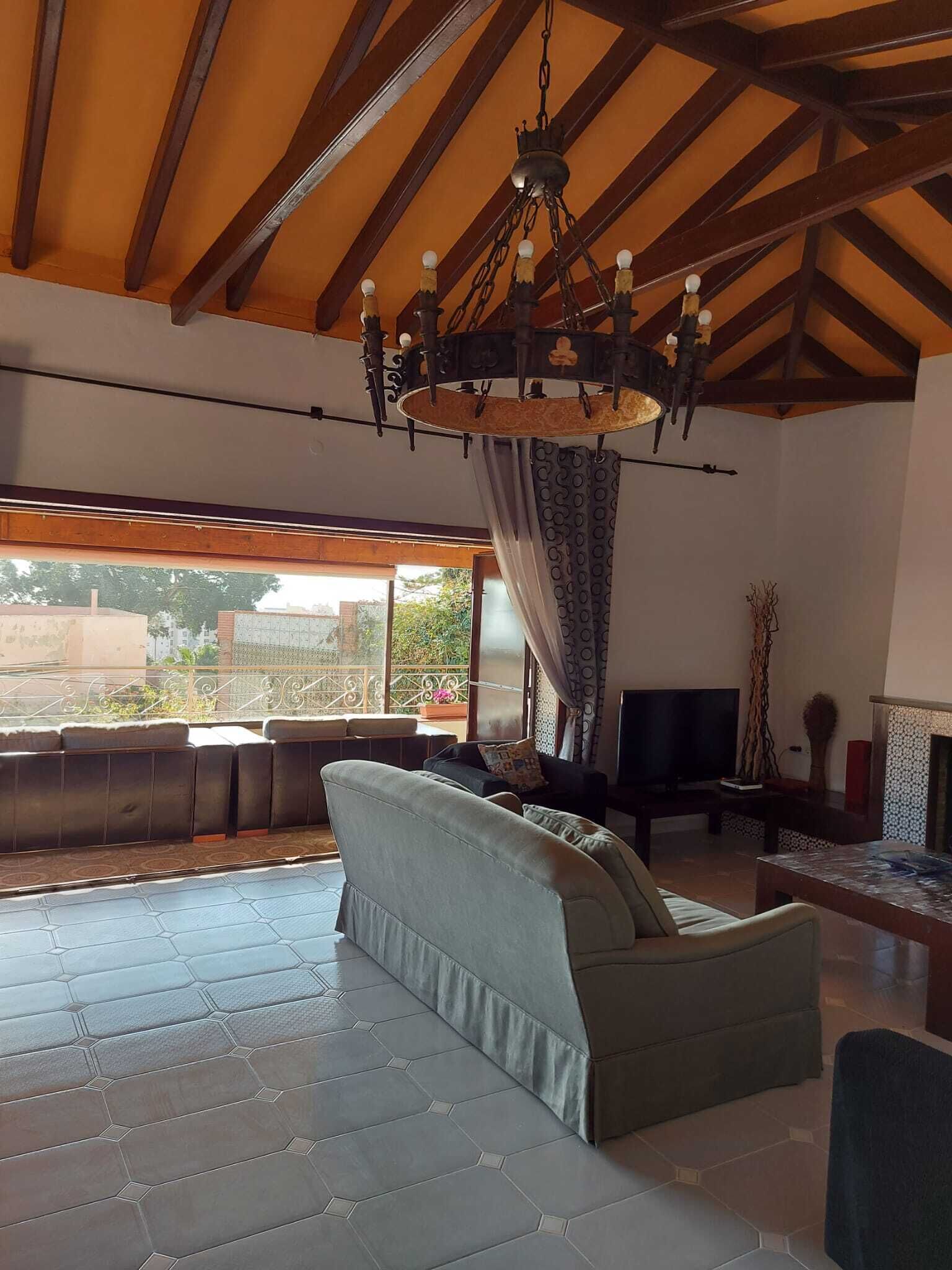 A spacious living room with a large sofa, a television, and a fireplace.