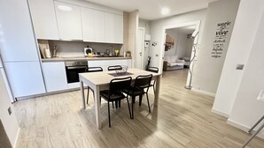 Een moderne keuken met witte kasten, een eettafel met stoelen en een houten vloer.