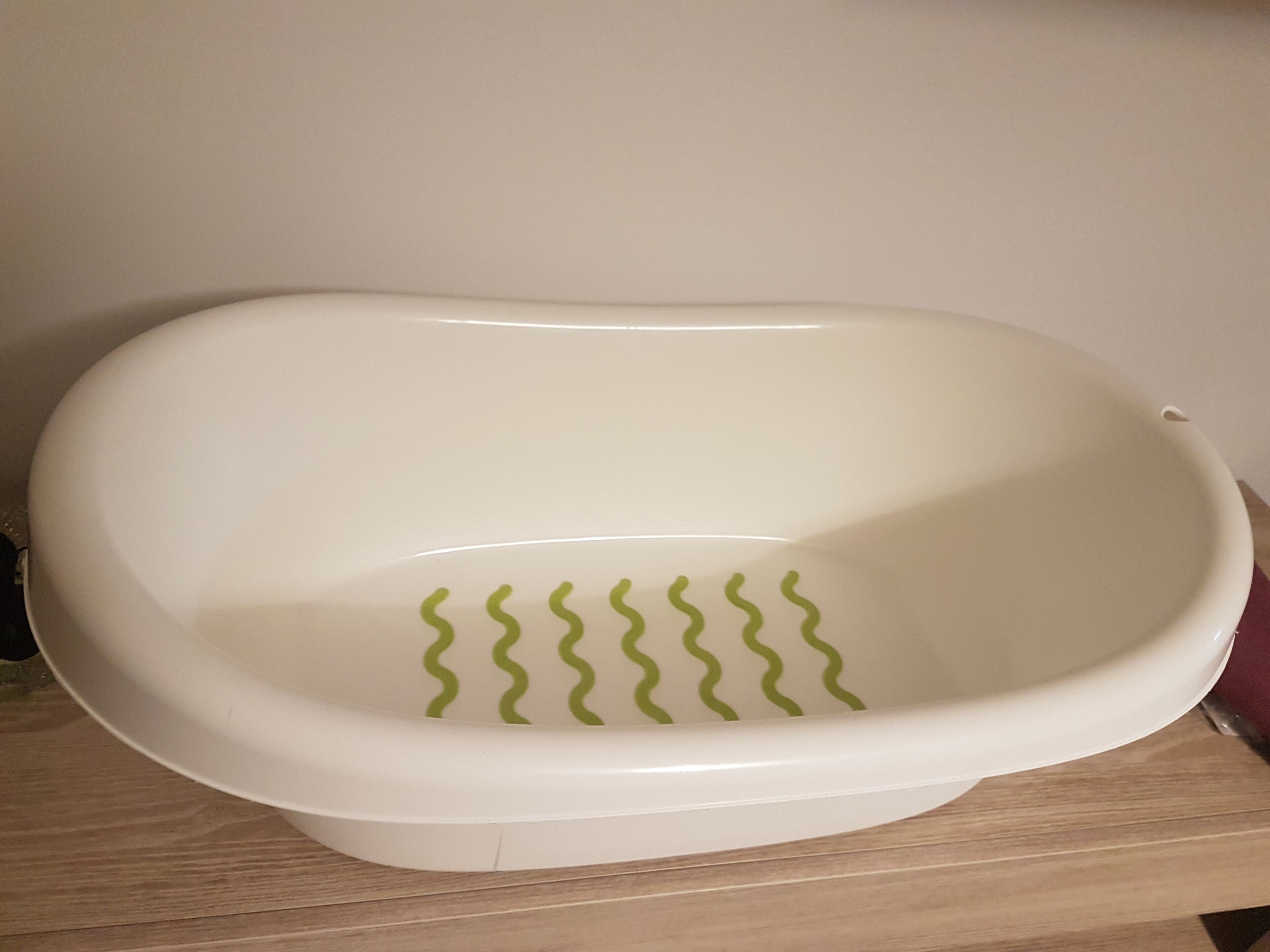 Una bañera blanca con líneas onduladas verdes en el fondo.