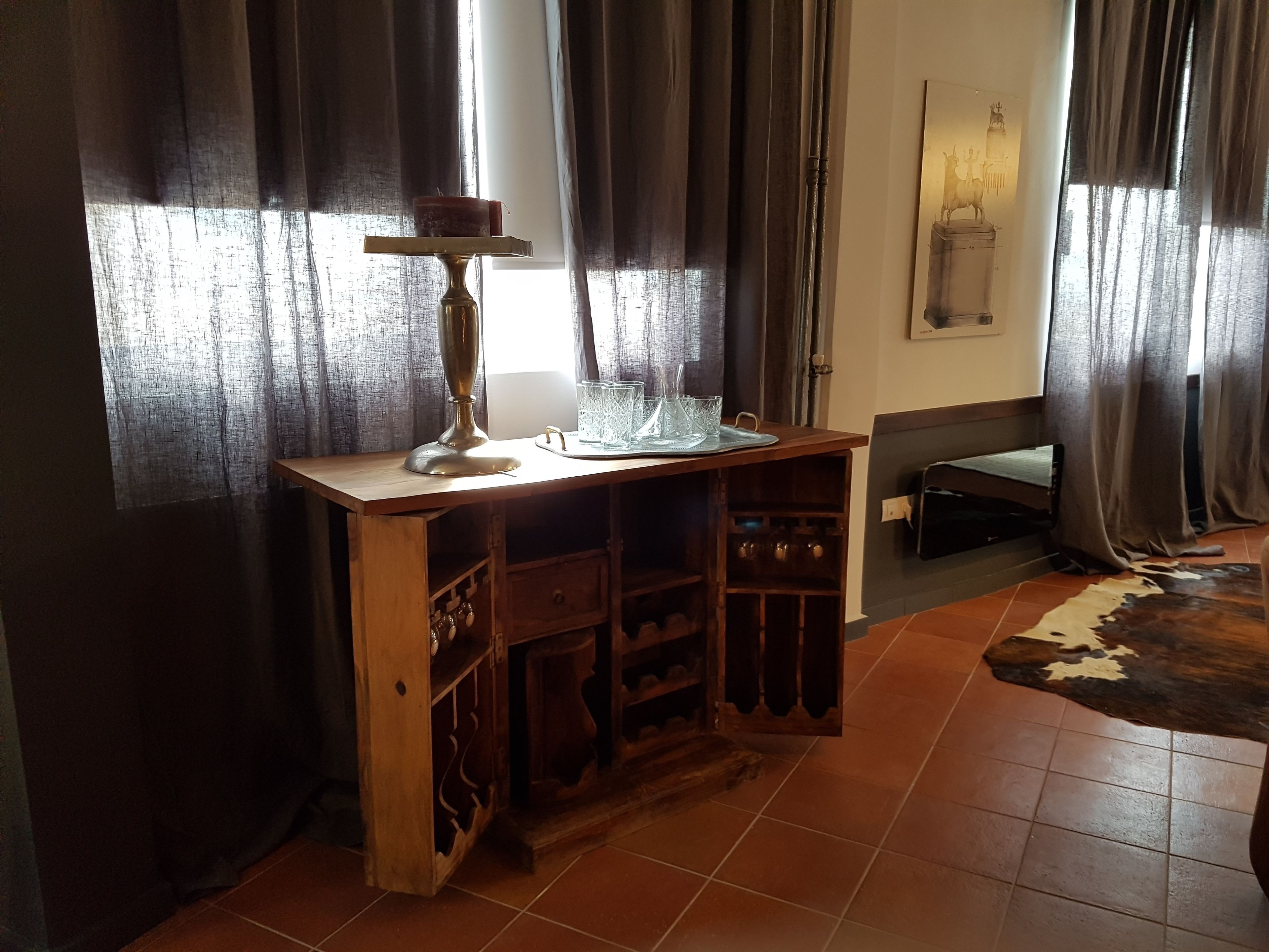 A wooden desk with a candle holder, glasses, and a tray.