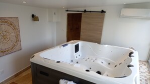 Een moderne badkamer met een vrijstaand ligbad, een houten deur en een mozaïek wanddecoratie.