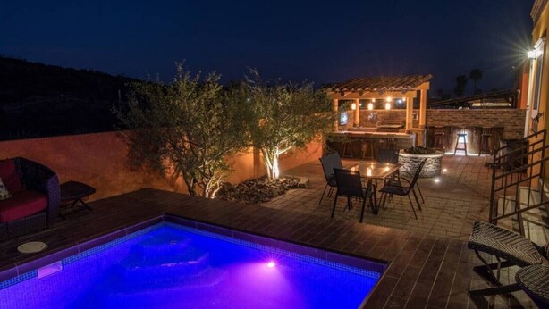 A swimming pool with a blue-lit edge, outdoor seating, and a barbecue area. - Beautiful house in San Carlos (SAN CARLOS)