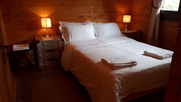 A neatly made bed with white linens and two bedside lamps.