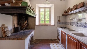 A compact kitchen with a window, a built-in stove, and a sink. - Farmhouse from the 1600s, former home of the Terrerosse Farm. (rimini)