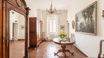 Una stanza con un tavolo rotondo in legno, un lampadario, un quadro grande incorniciato e uno specchio.