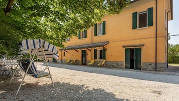 Un edificio con vialetto sterrato, posti a sedere all'aperto e una zona patio coperta.