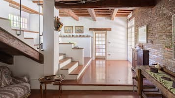 Un'ampia stanza con parquet, una scala e un muro in mattoni.