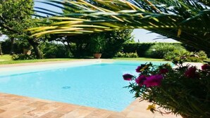 A swimming pool surrounded by lush greenery and a well-maintained garden. - Farmhouse from the 1600s, former home of the Terrerosse Farm. (rimini)