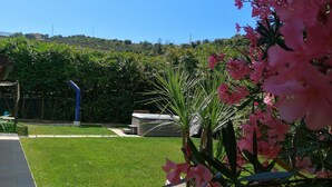 Un jardín bien cuidado con un sendero despejado, un jacuzzi y abundante vegetación.