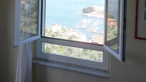 Une chambre dotée d’une grande fenêtre donnant sur un port de plaisance et la mer.