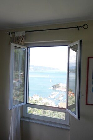 Enjoy a serene view of the water from this room's large window, which offers a glimpse of a marina and distant buildings.