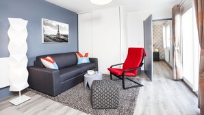 Un salon moderne avec un canapé gris, un fauteuil rouge et un tapis à motifs.