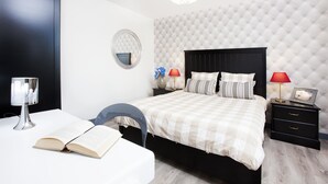 Une chambre à coucher avec un lit, des tables de chevet, un miroir, une lampe et une chaise.