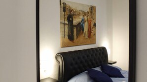 A bedroom with a bed, a headboard, a nightstand, and a painting on the wall. - NEW SWEET FLORENCE (at T2 Belfiore) (Firenze)