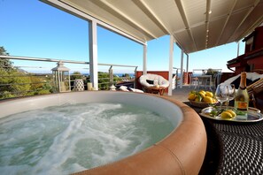 A hot tub with a view of the sea, surrounded by wicker furniture and a table with lemons and a bottle. - Villa Giovanna with terrace, jacuzzi and sauna (LOANO)