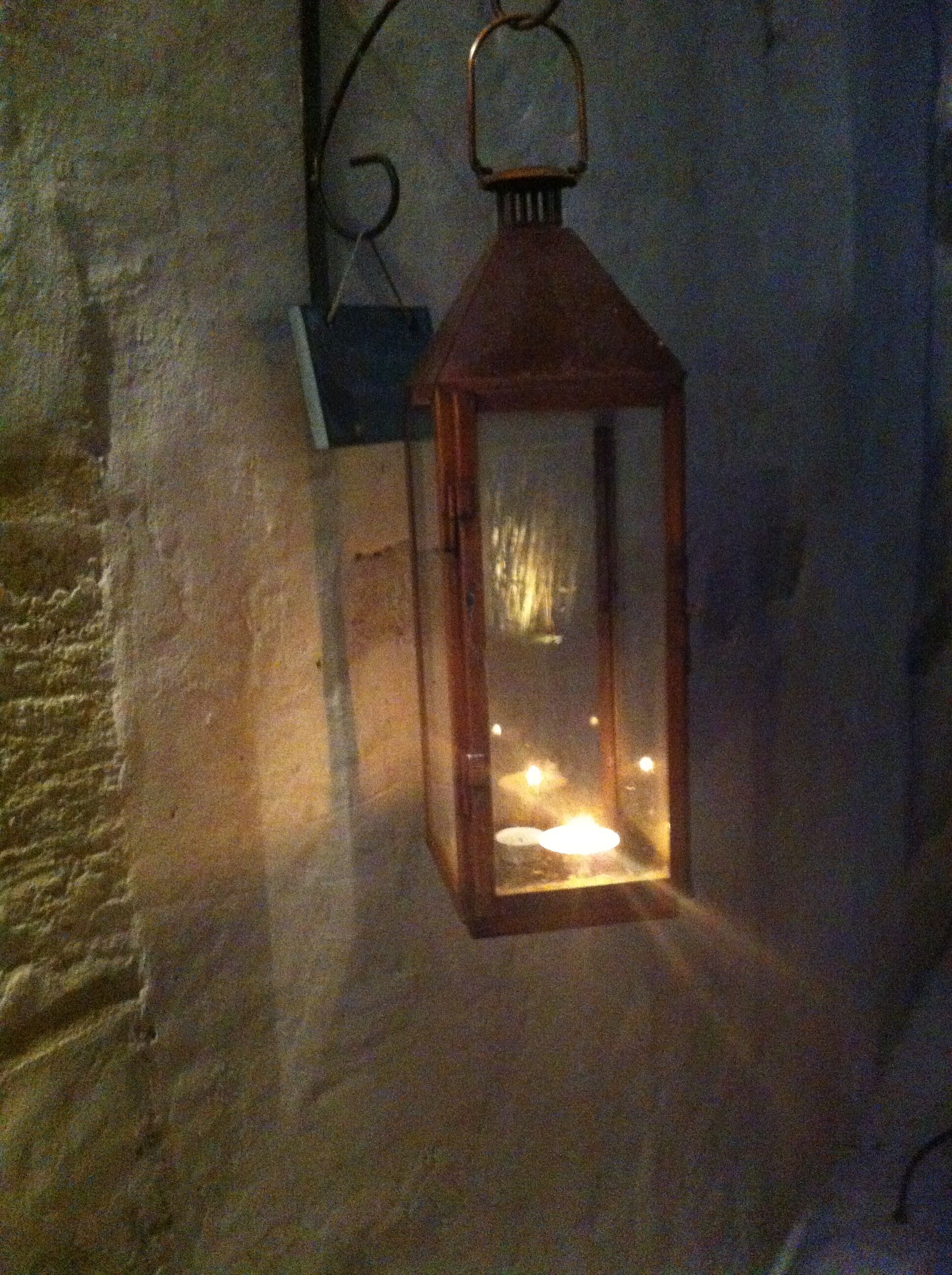 Un farol colgando de una pared con textura.