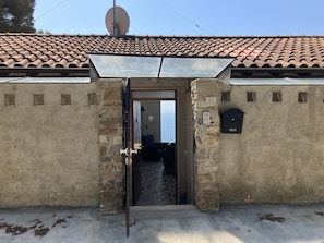 Un bâtiment rustique avec un toit en tuiles, une antenne parabolique et une boîte aux lettres.