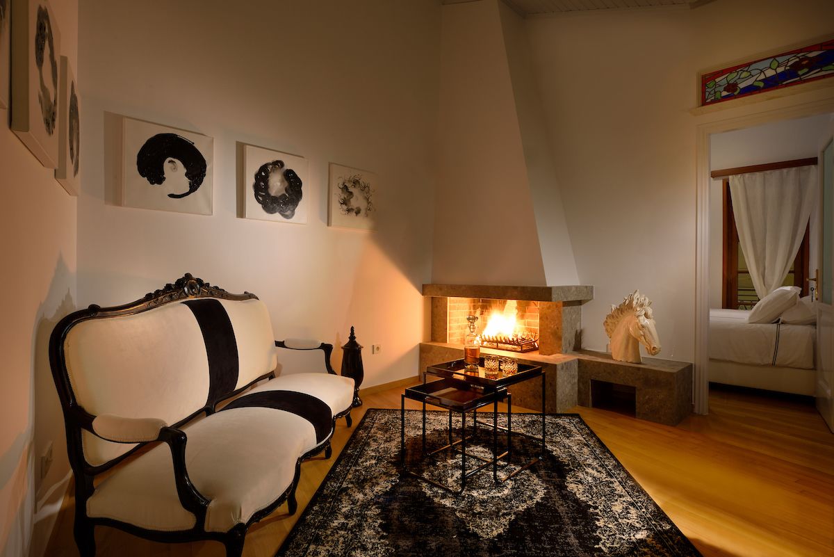 A cozy living room with a fireplace, a classic armchair, and a coffee table.