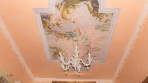Un soffitto con un affresco floreale e un lampadario.