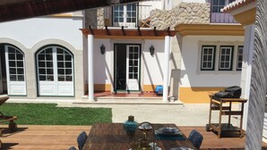 An outdoor dining area with a wooden table set for four, surrounded by chairs.
