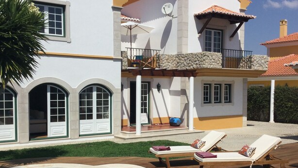 A two-story house with a swimming pool, a balcony, and a garden.