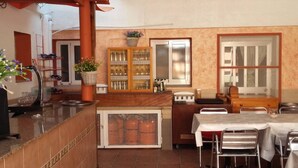 Una cocina con salpicadero de azulejos, encimera de madera, pileta, estufa y comedor con mesa y sillas.